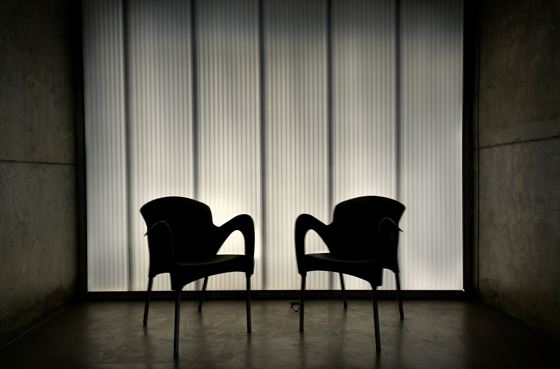Two empty armchairs facing one another in a dim room